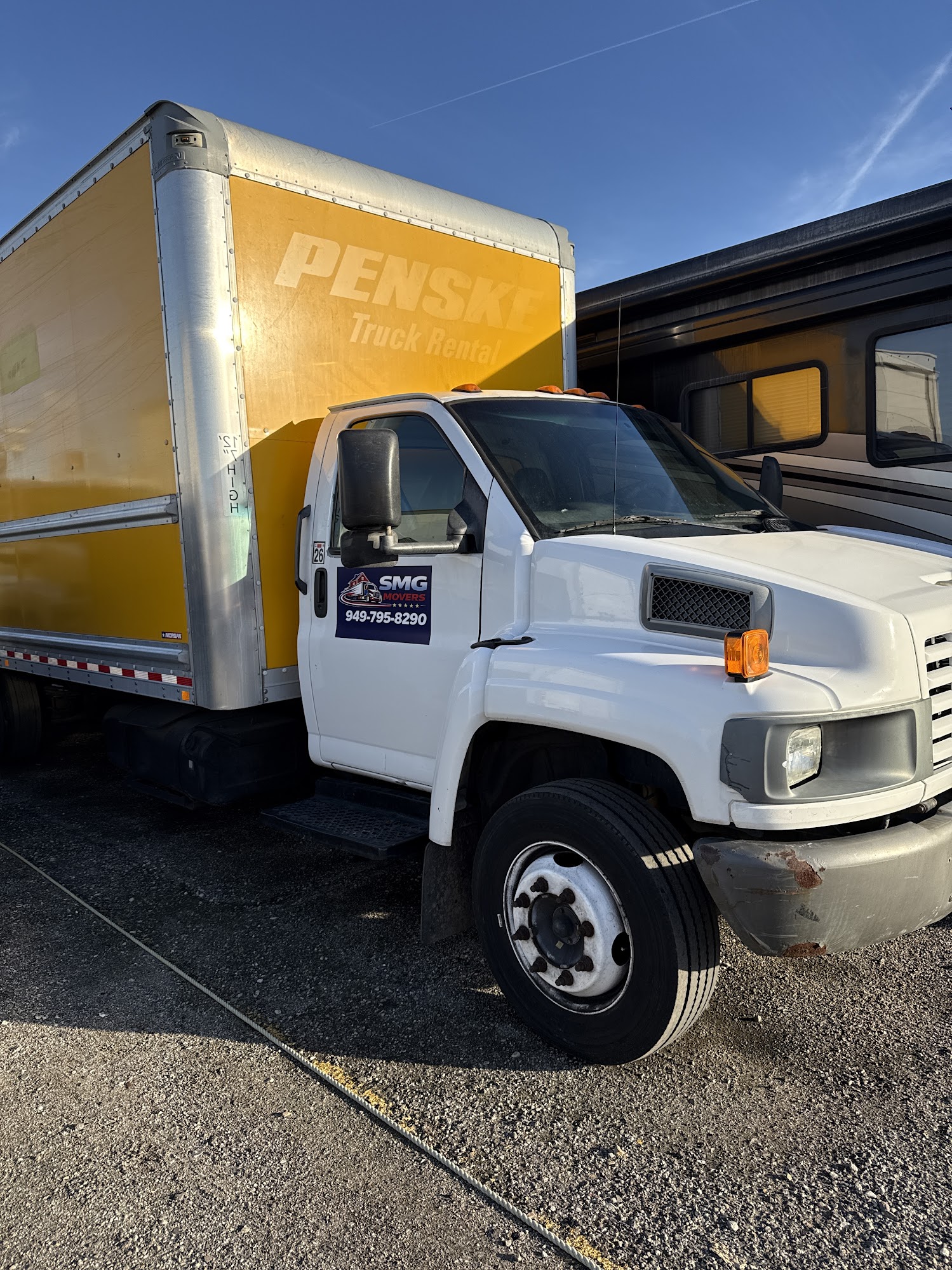 Professional movers loading stacked moving boxes onto hydraulic truck ramp in Costa Mesa